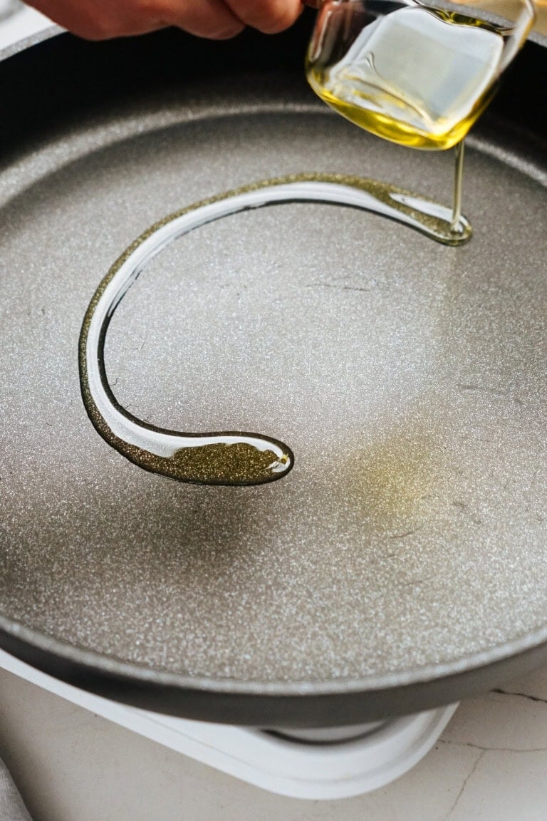 Preparing a delicious Salisbury steak recipe starts with pouring oil into a frying pan on the stovetop.