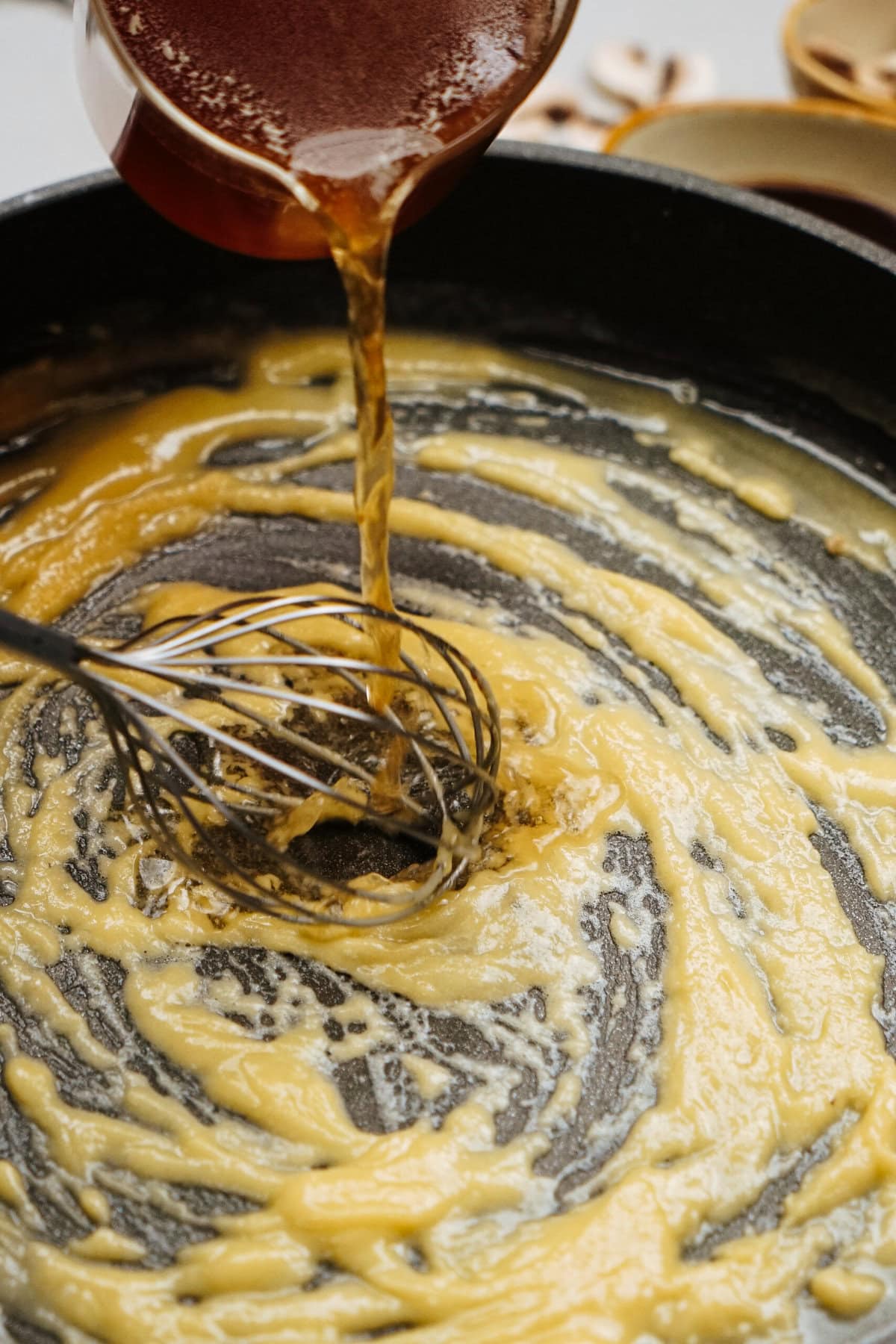 Honey cascades into a sizzling pan, joining the mixture as a whisk expertly stirs, enhancing the flavors of this delightful Salisbury steak recipe.