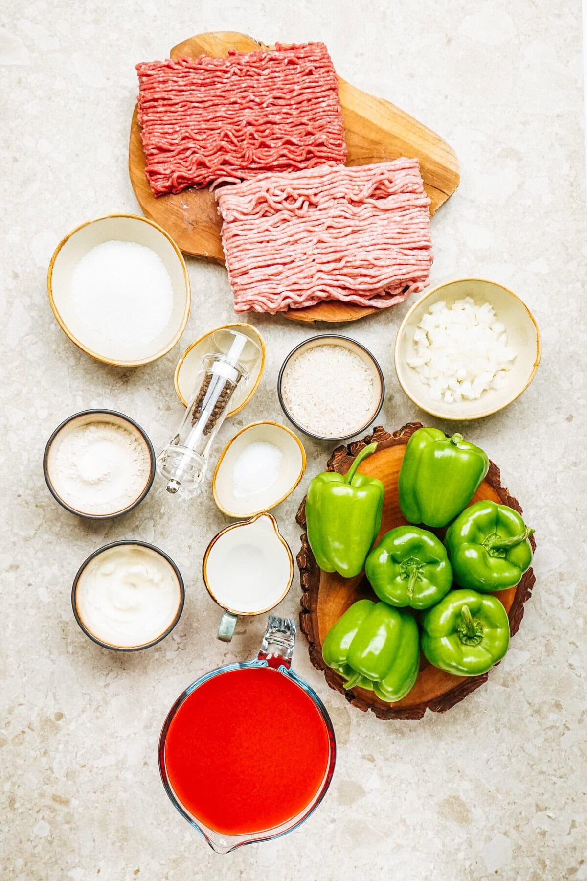 Ingredients for delicious stuffed peppers on a countertop: ground beef, pork, green peppers, diced onions, rice, tomato sauce, sour cream, flour, sugar, salt, pepper, and milk. Perfect for creating a classic stuffed peppers dish that'll delight your taste buds!.