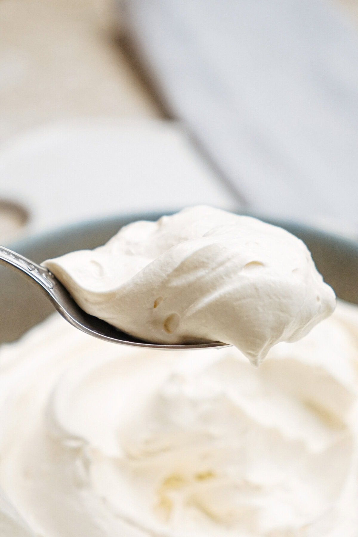 A spoonful of whipped cream held above a bowl of more whipped cream.