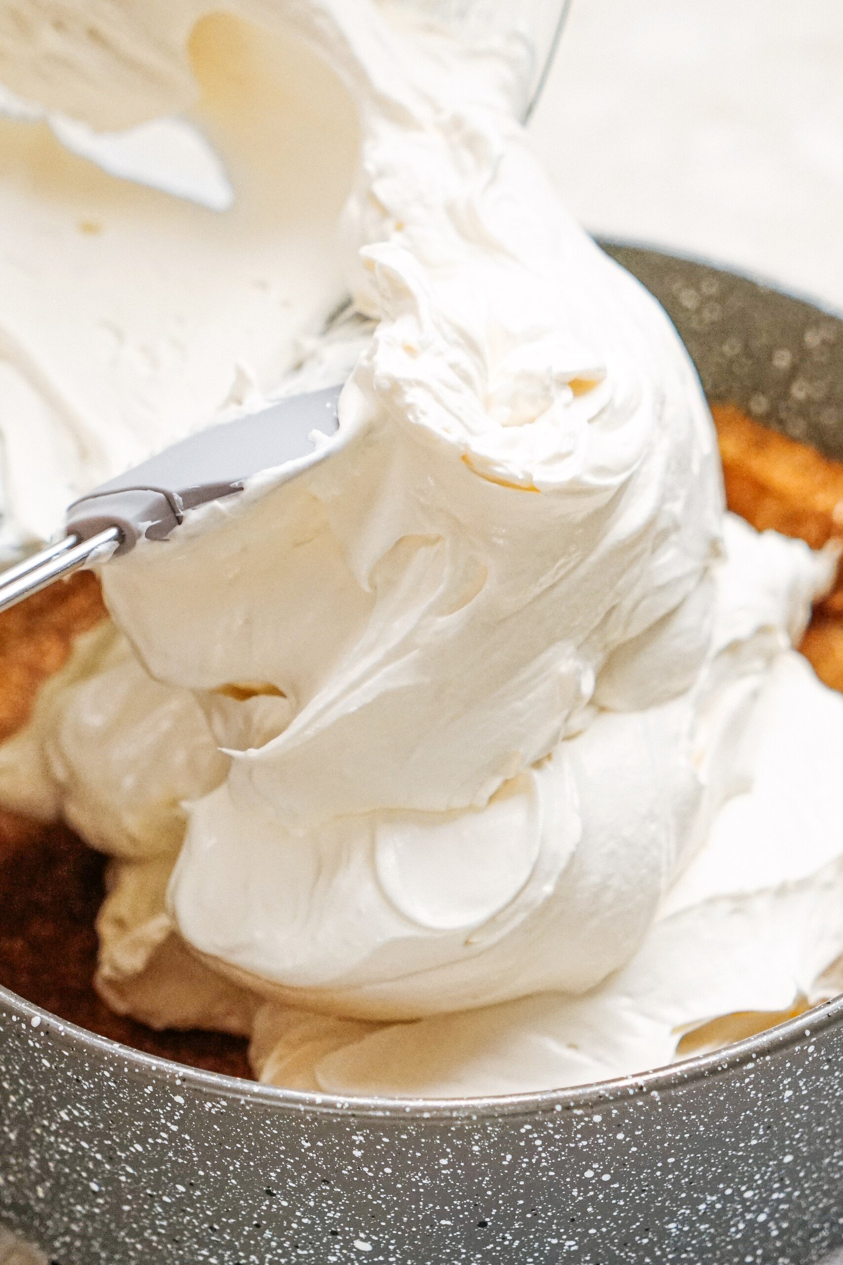 Spreading No Bake Cheesecake Filling over a graham cracker crust in a round metal pan.