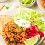 Delicious homemade taco rice with seasoned meat, fresh vegetables, and lime wedges.