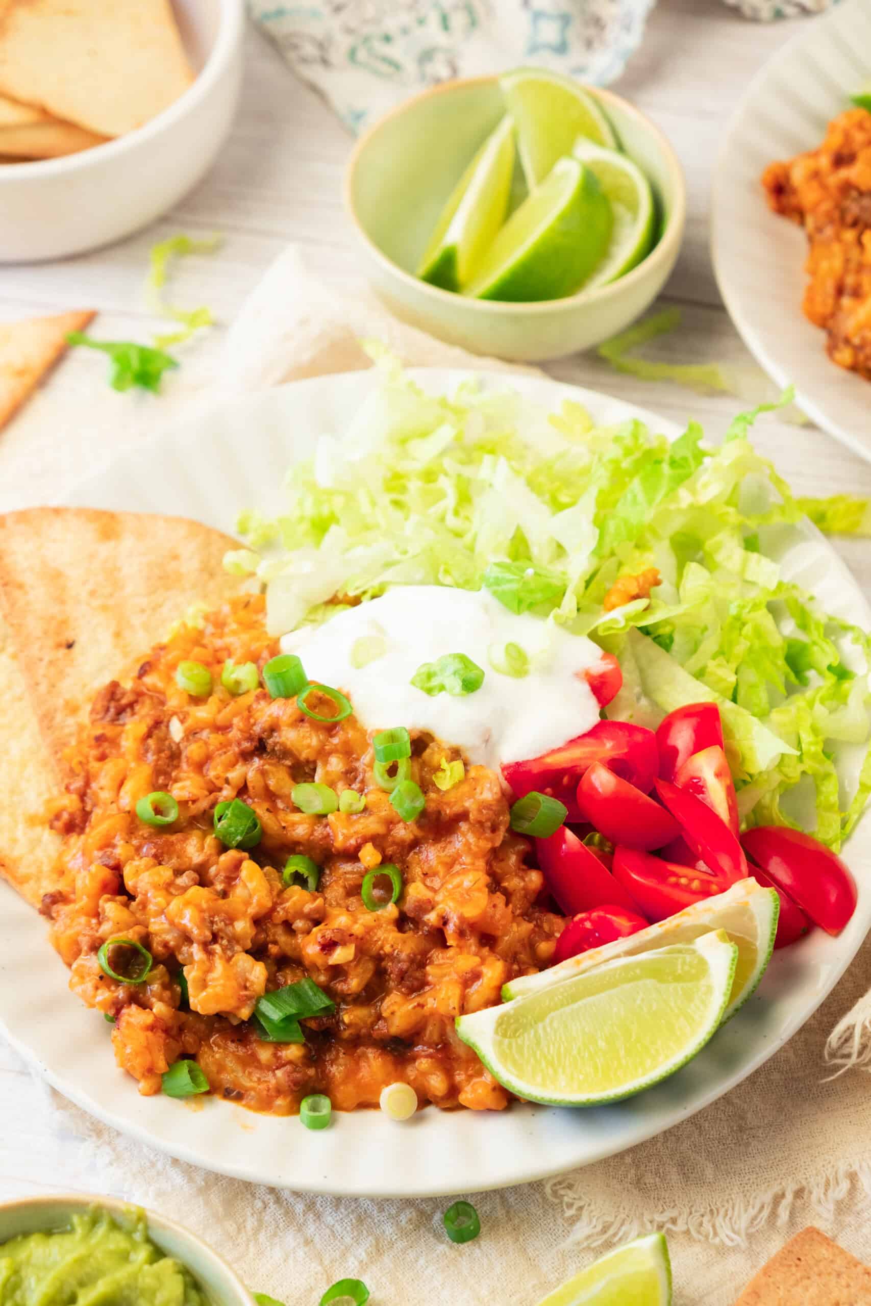 Delicious homemade taco rice with seasoned meat, fresh vegetables, and lime wedges.