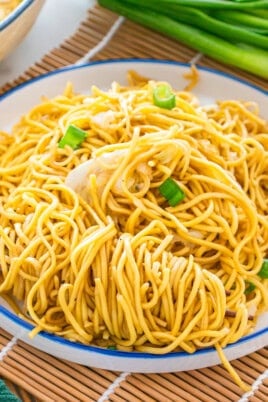 A plate of stir-fried noodles with shredded cabbage and green onions, served with chopsticks on a white plate—an easy chow mein recipe perfect for a quick meal.
