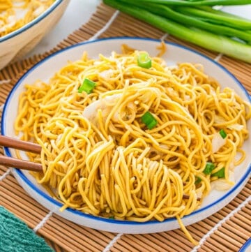 A plate of stir-fried noodles with shredded cabbage and green onions, served with chopsticks on a white plate—an easy chow mein recipe perfect for a quick meal.