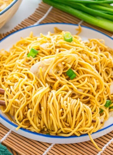 A plate of stir-fried noodles with shredded cabbage and green onions, served with chopsticks on a white plate—an easy chow mein recipe perfect for a quick meal.