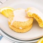 Delicious lemon sugar cookies topped with sweet icing, served on a white plate with fresh lemon slice.