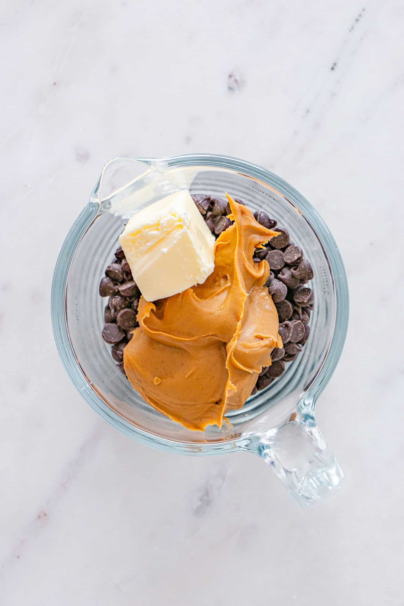 Chocolate chips, peanut butter, and butter in a glass measuring cup.