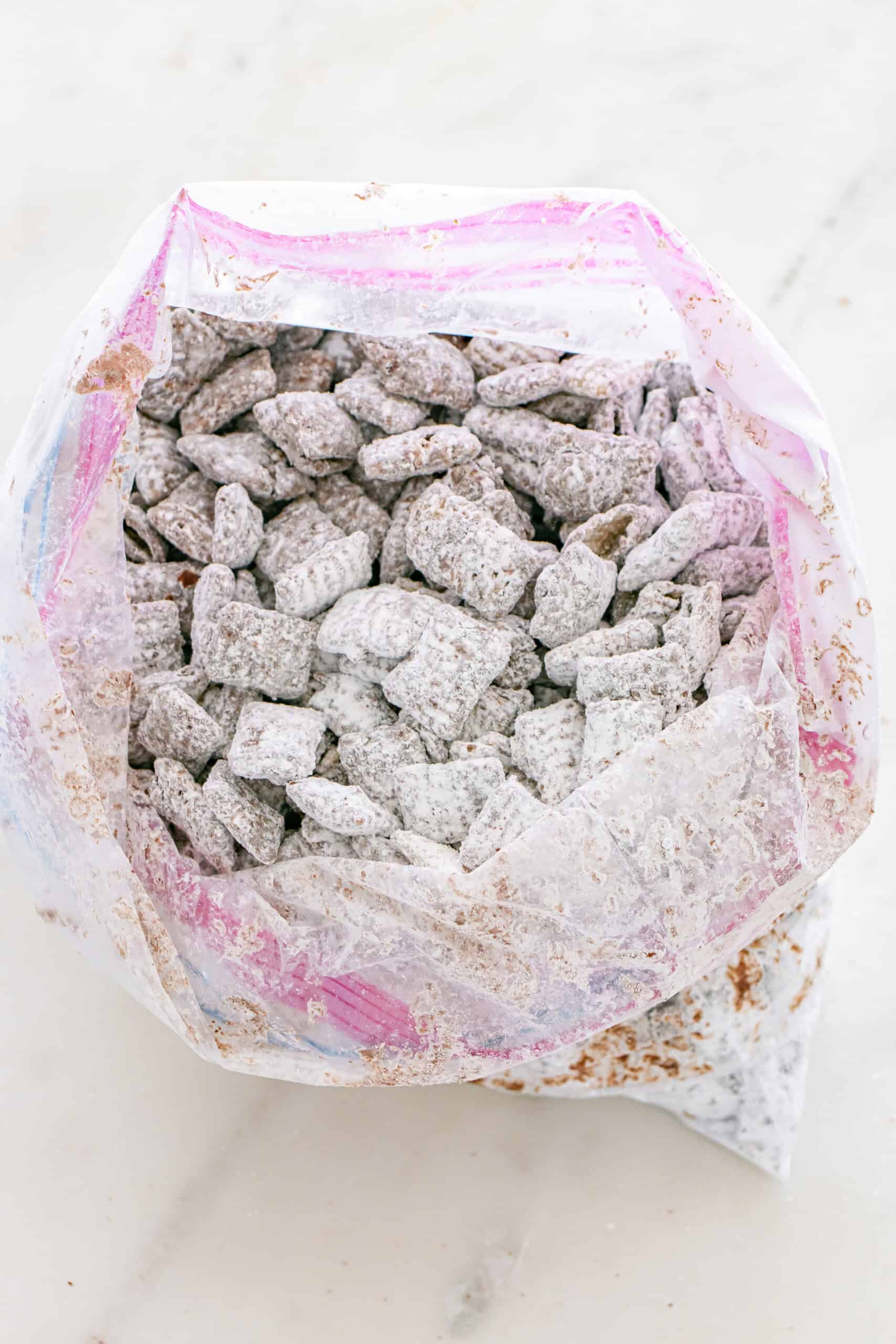 Puppy chow coated in powdered sugar inside a zip top bag.