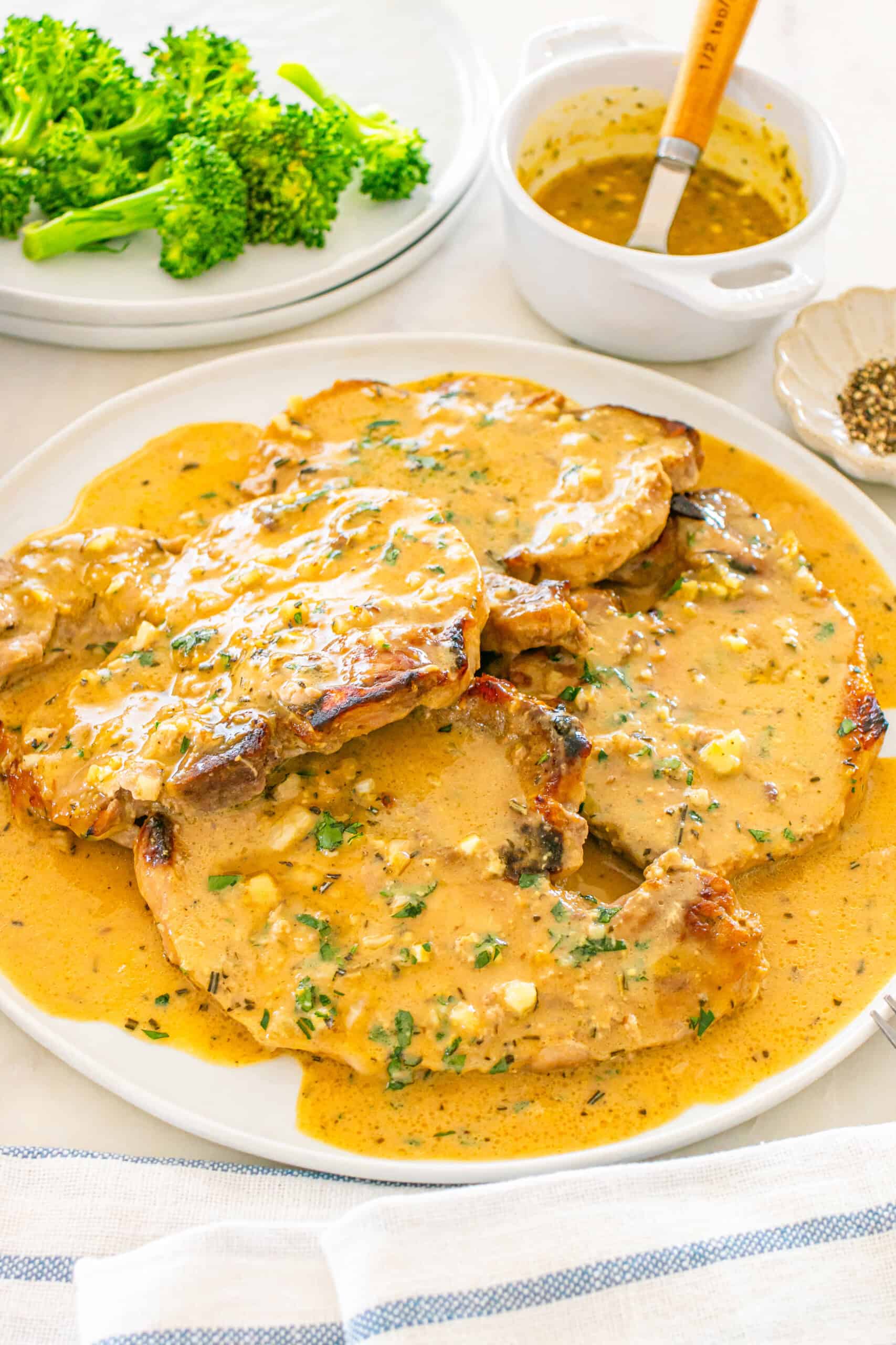 Juicy pork chops are seasoned with a rich sauce and served with broccoli.