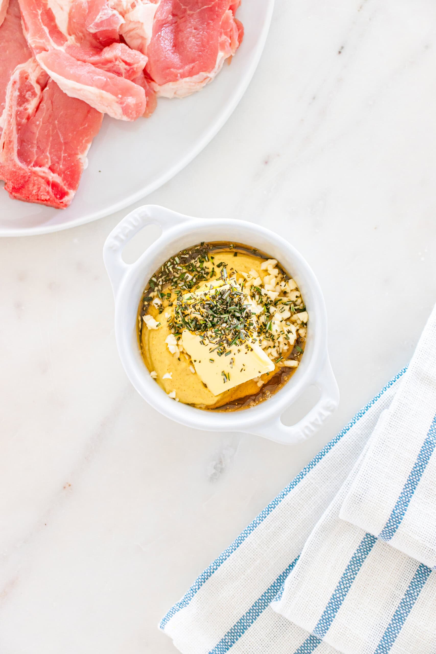 Raw meat with herb butter on white marble surface for cooking and grilling.