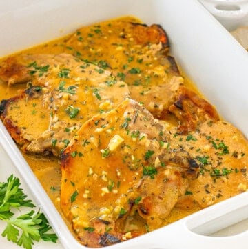 Delicious grilled pork chops in herb sauce and garnished with fresh parsley.