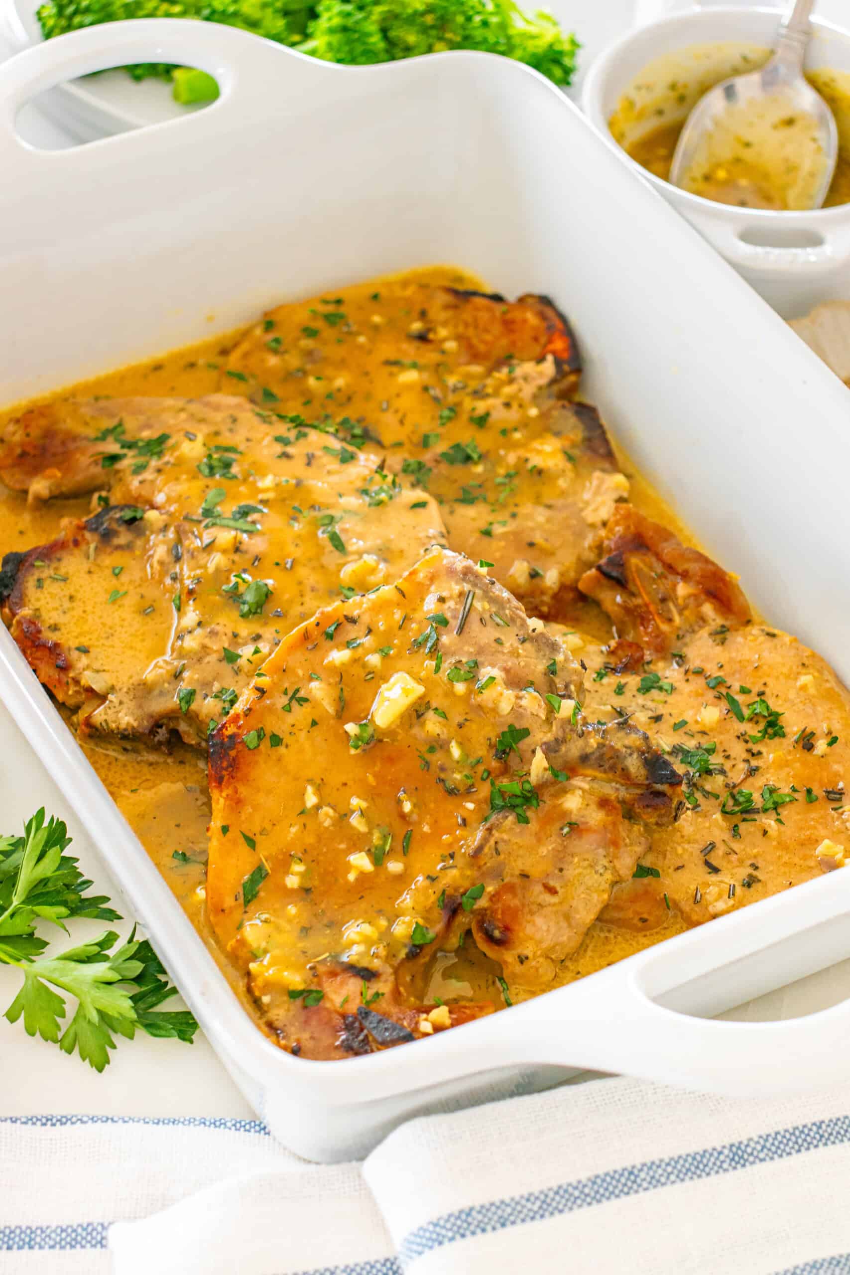 Delicious grilled pork chops in herb sauce and garnished with fresh parsley.