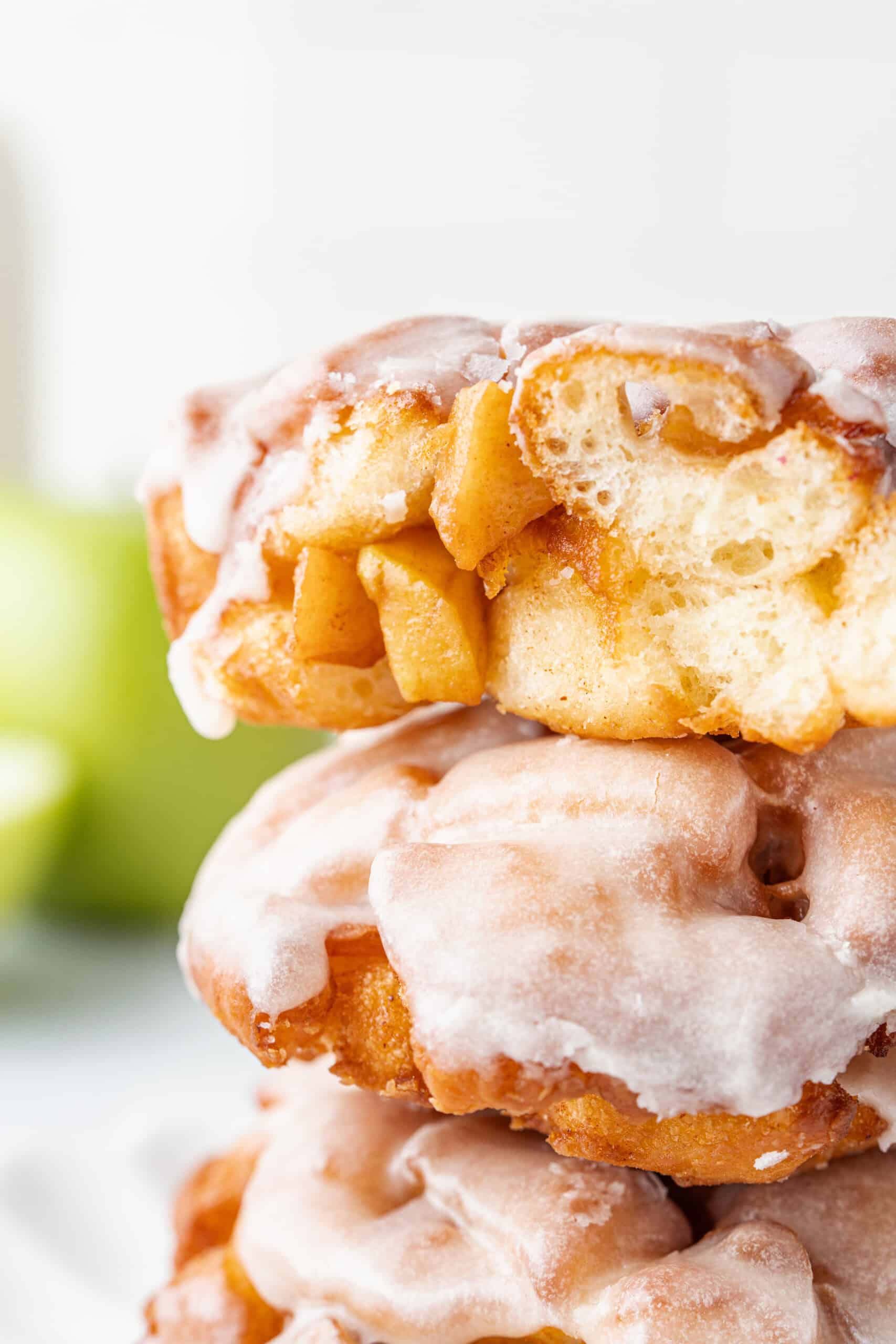 Stack of glazed apple fritters with apple filling visible in the center.