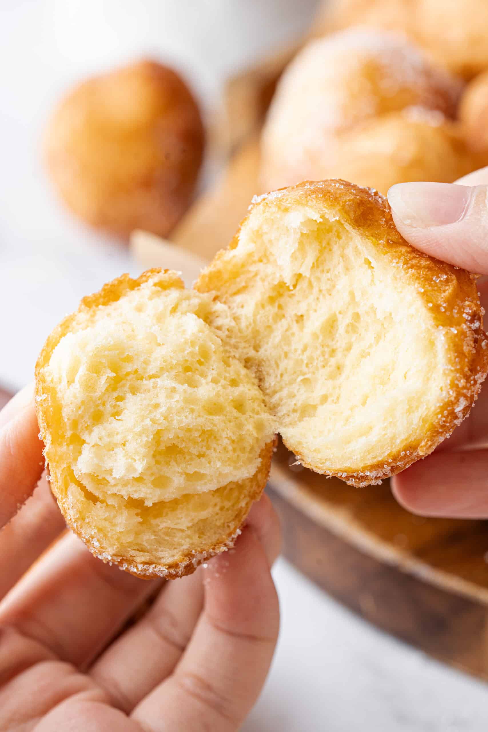 Close-up of a sugar-coated donut hole split open to reveal its soft, fluffy center.