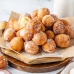 A tray piled with sugar-coated donut holes on parchment paper