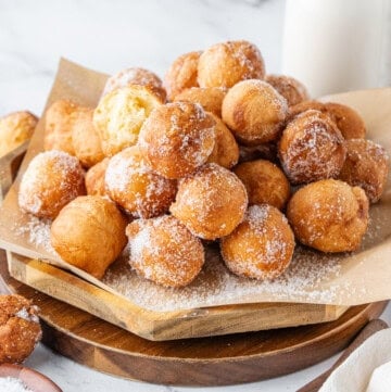 A tray piled with sugar-coated donut holes on parchment paper