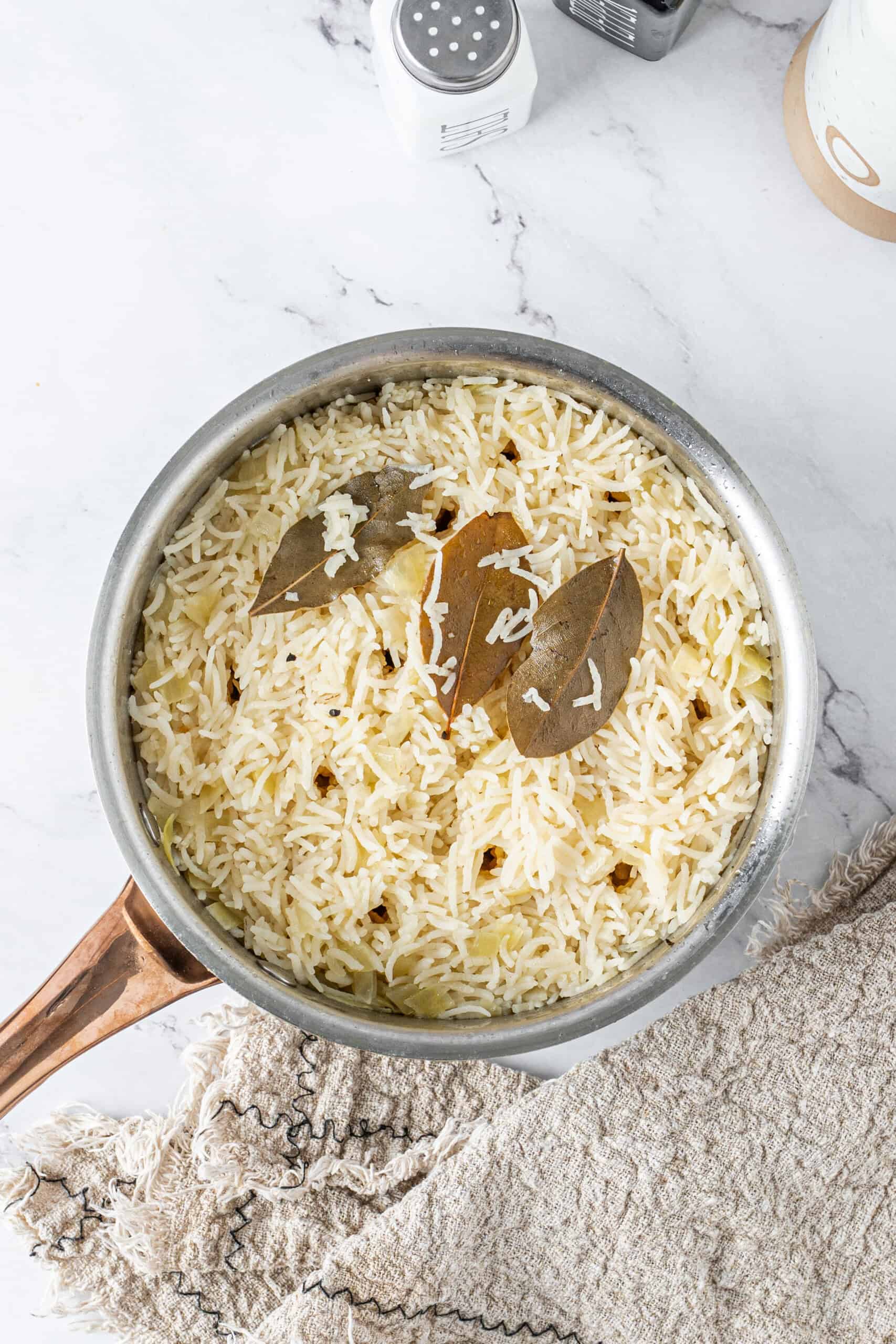 Fluffy butter rice with onions and bay leaves in a saucepan after cooking.