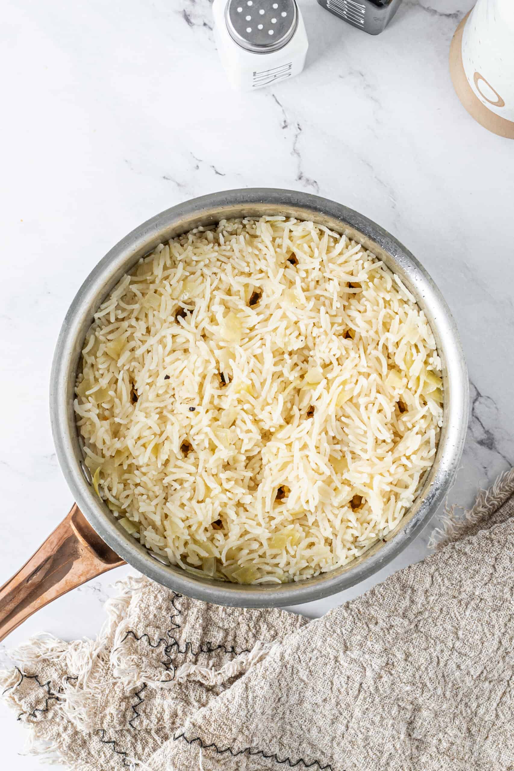 Fluffy butter rice with tender onions in a saucepan after cooking.