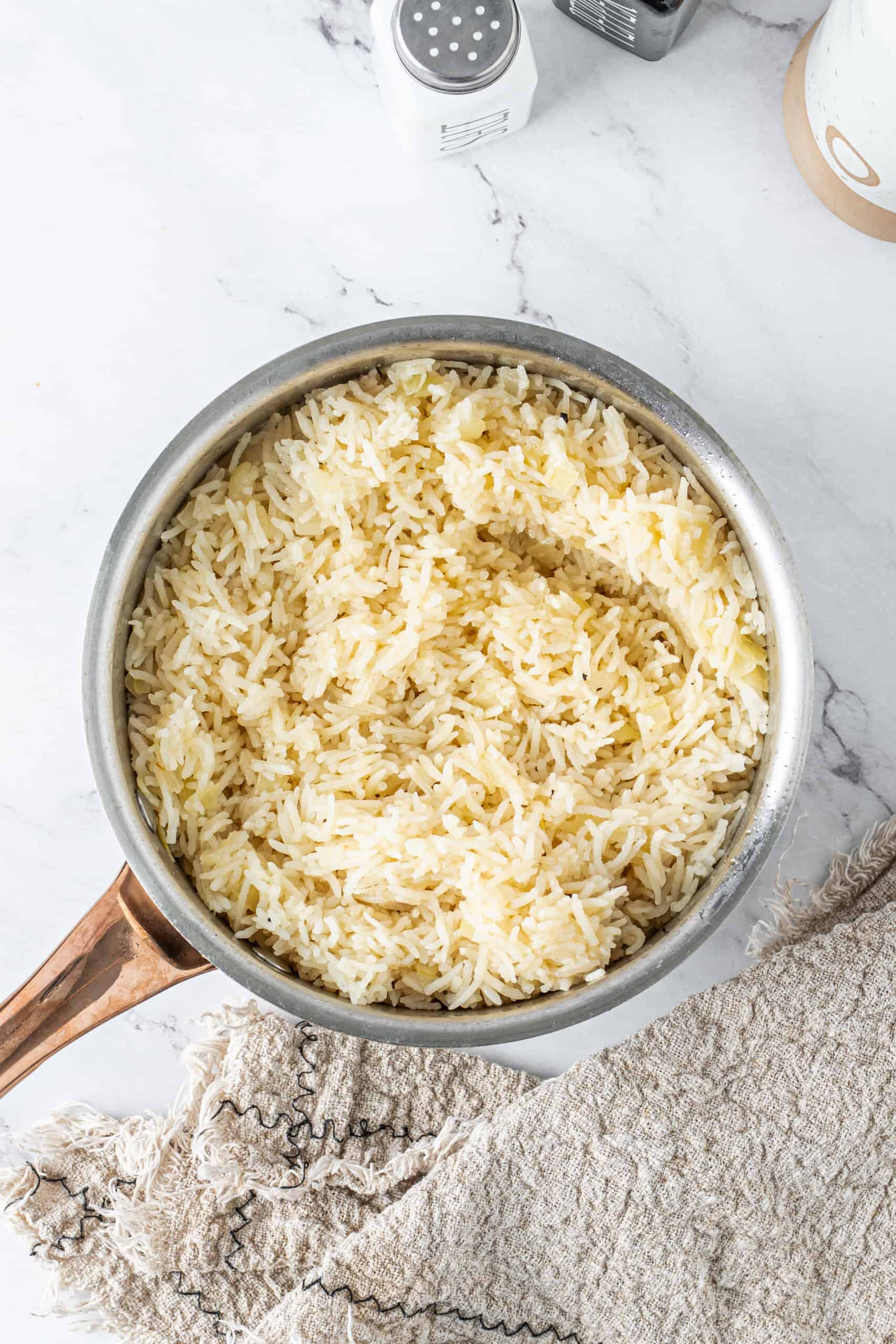 Fluffy butter rice after fluffing with a fork in the saucepan.