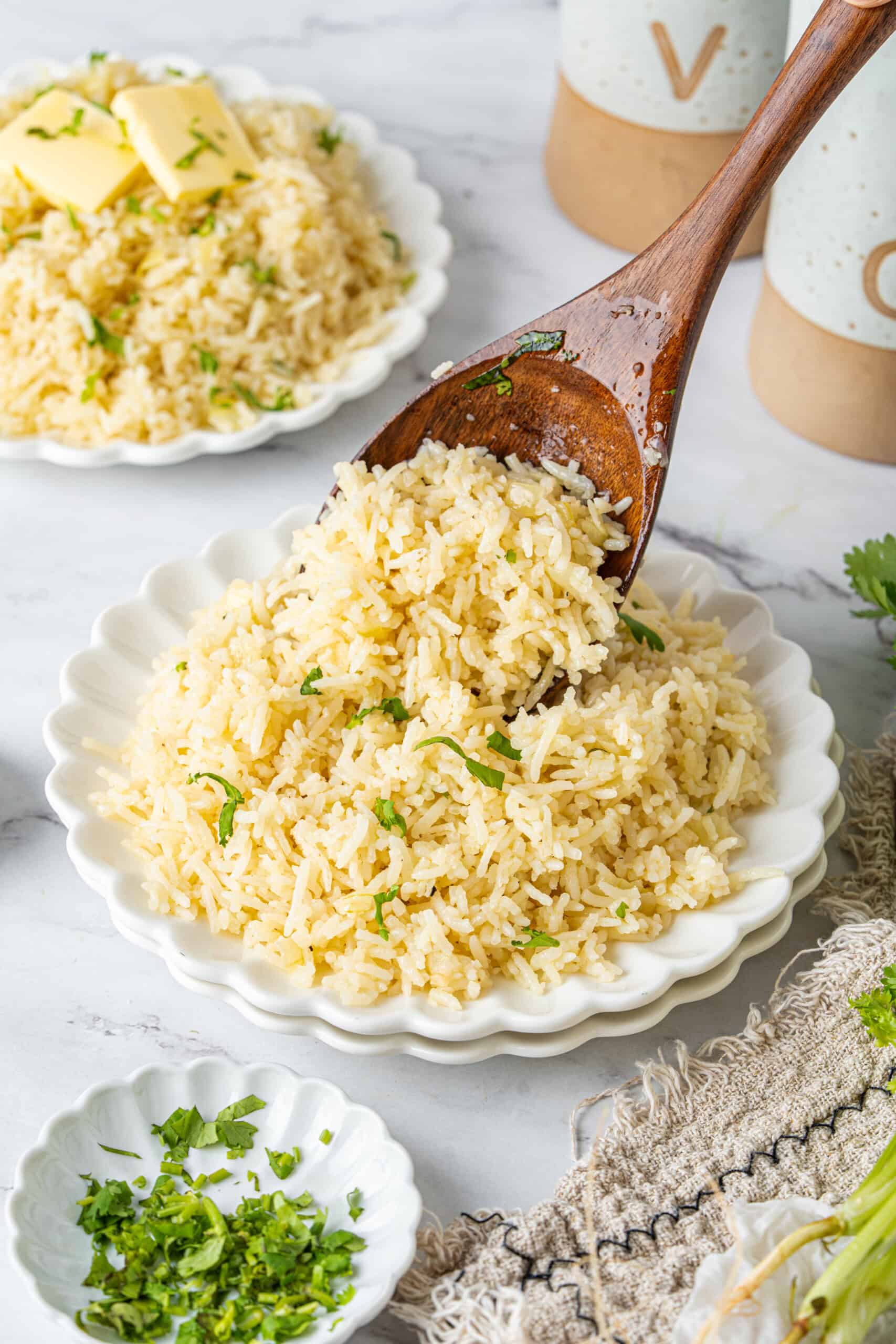Spoon serving fluffy butter rice with parsley onto a plate