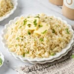 Plate of fluffy butter rice topped with melting butter and fresh parsley.