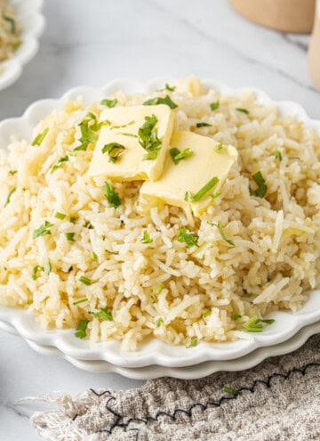Plate of fluffy butter rice topped with melting butter and fresh parsley.