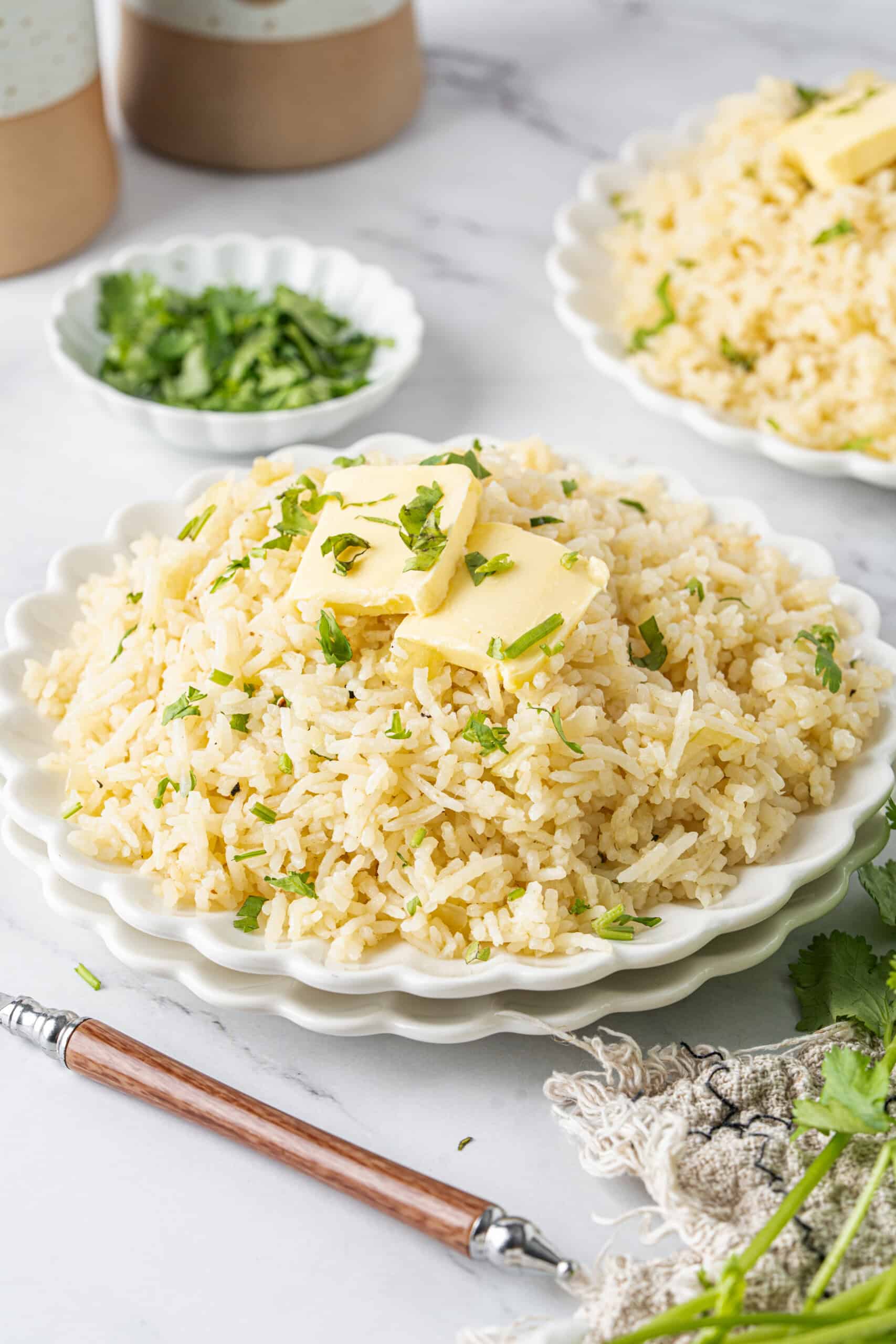 Butter rice served on a plate with butter slices and fresh parsley on top.