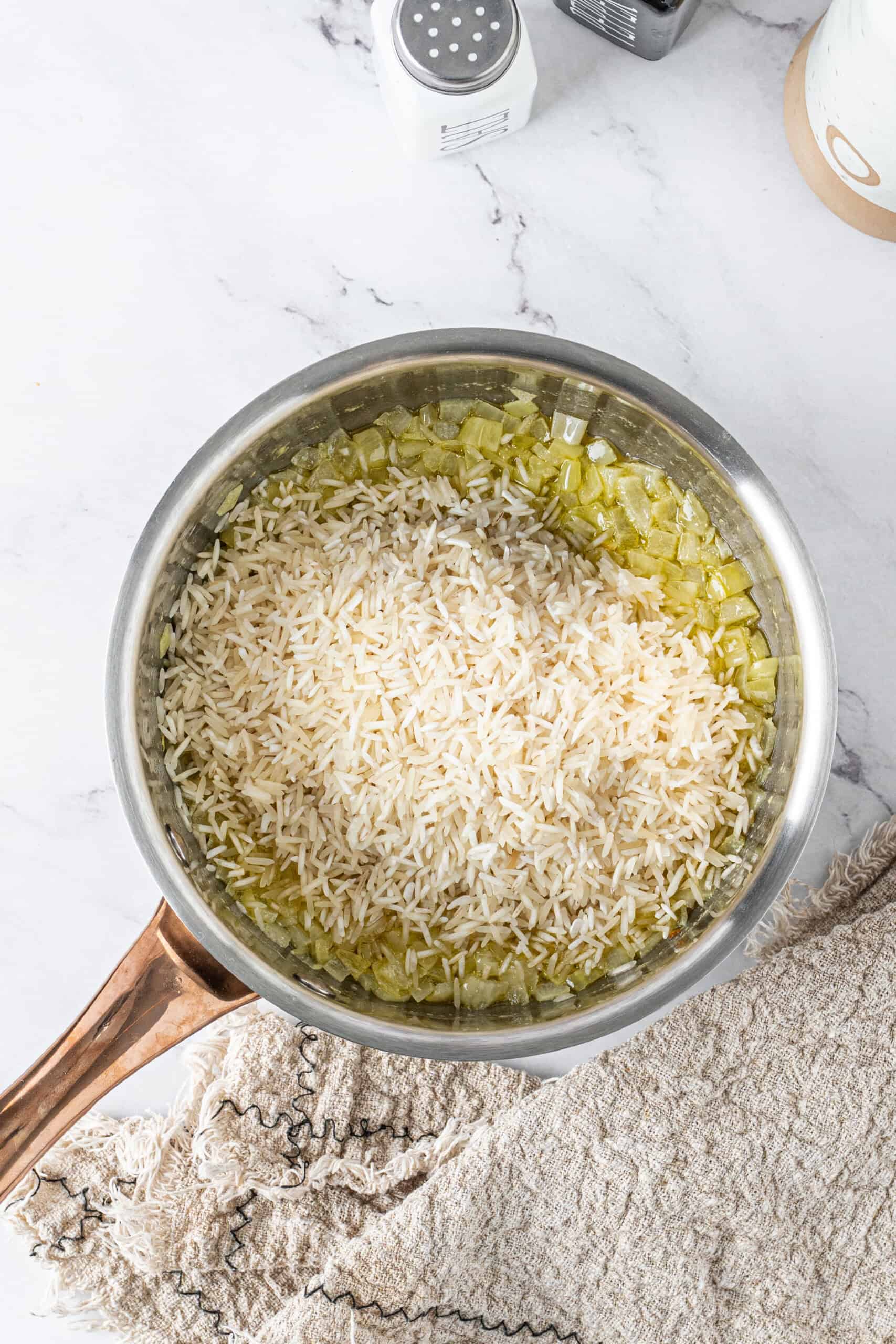 White rice added to butter and onions in a saucepan