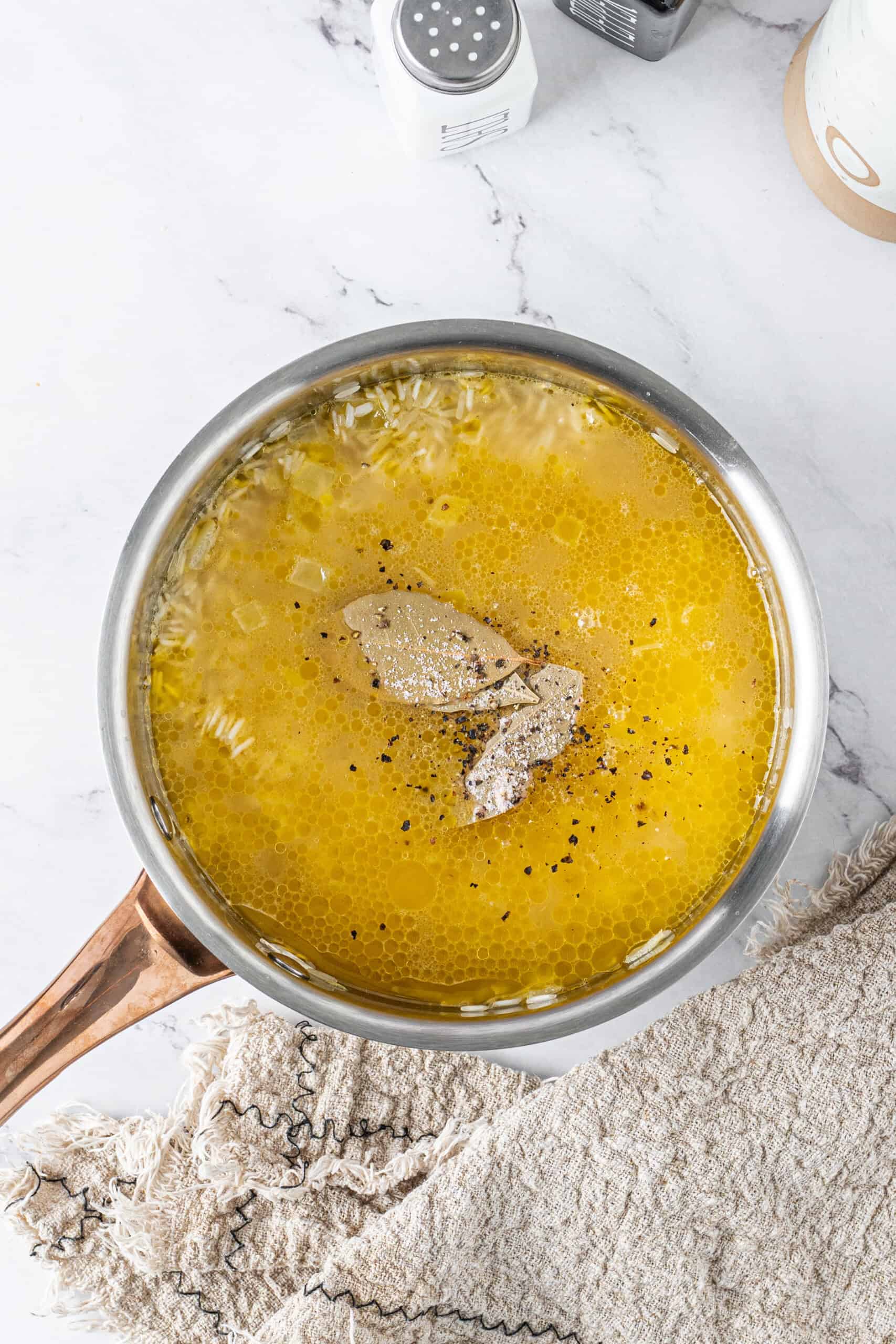 Chicken broth, rice, bay leaves, and seasonings in a saucepan