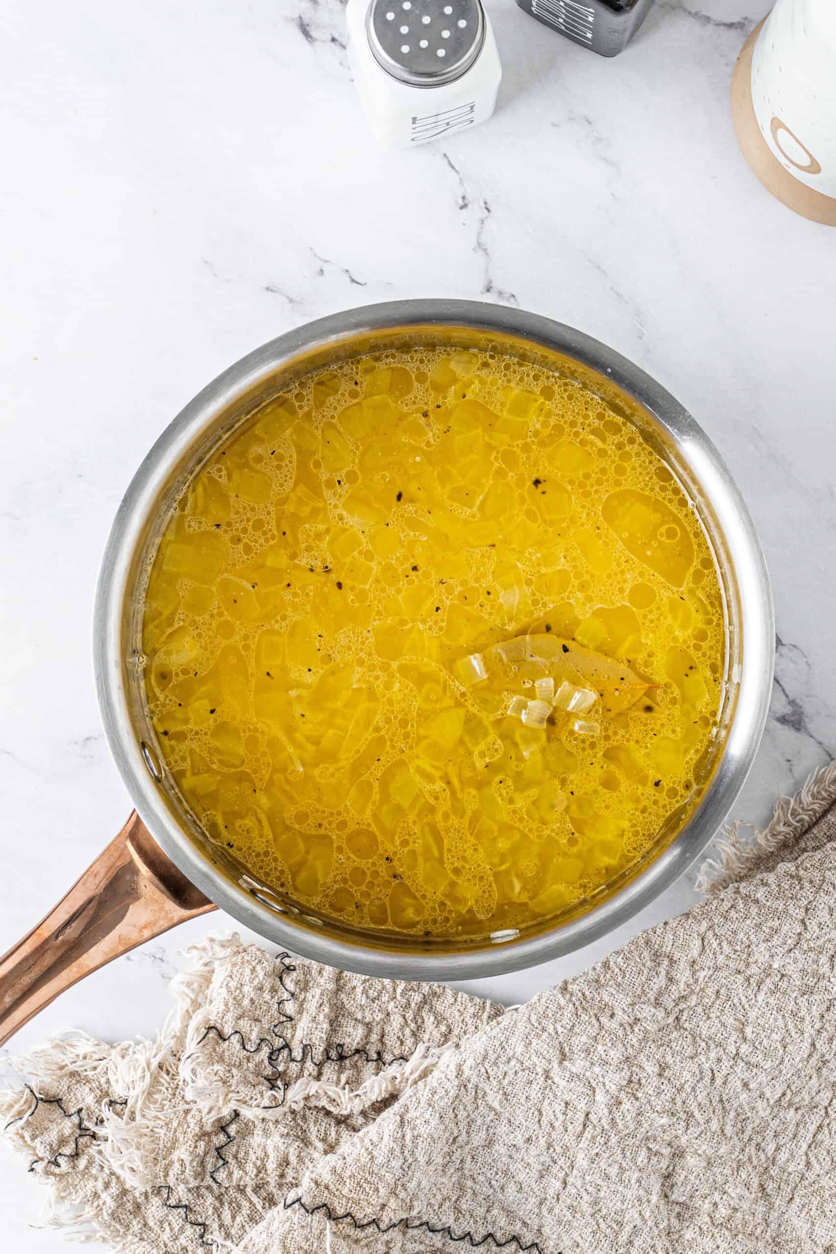 Chicken broth, rice, bay leaves, and seasonings in a saucepan