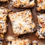 Overhead view of homemade magic bars topped with toasted coconut, pecans, chocolate chips, and butterscotch chips.