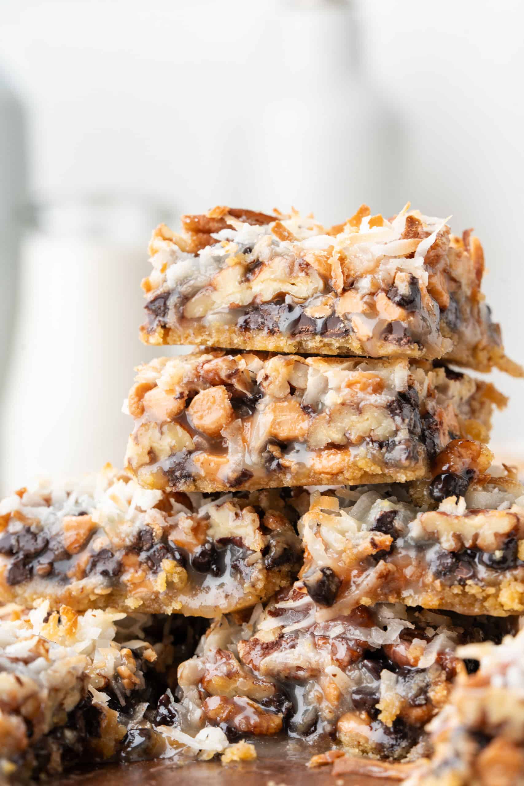 Stacked Hello Dolly Bars with layers of chocolate chips, butterscotch chips, coconut, pecans, and graham cracker crust.