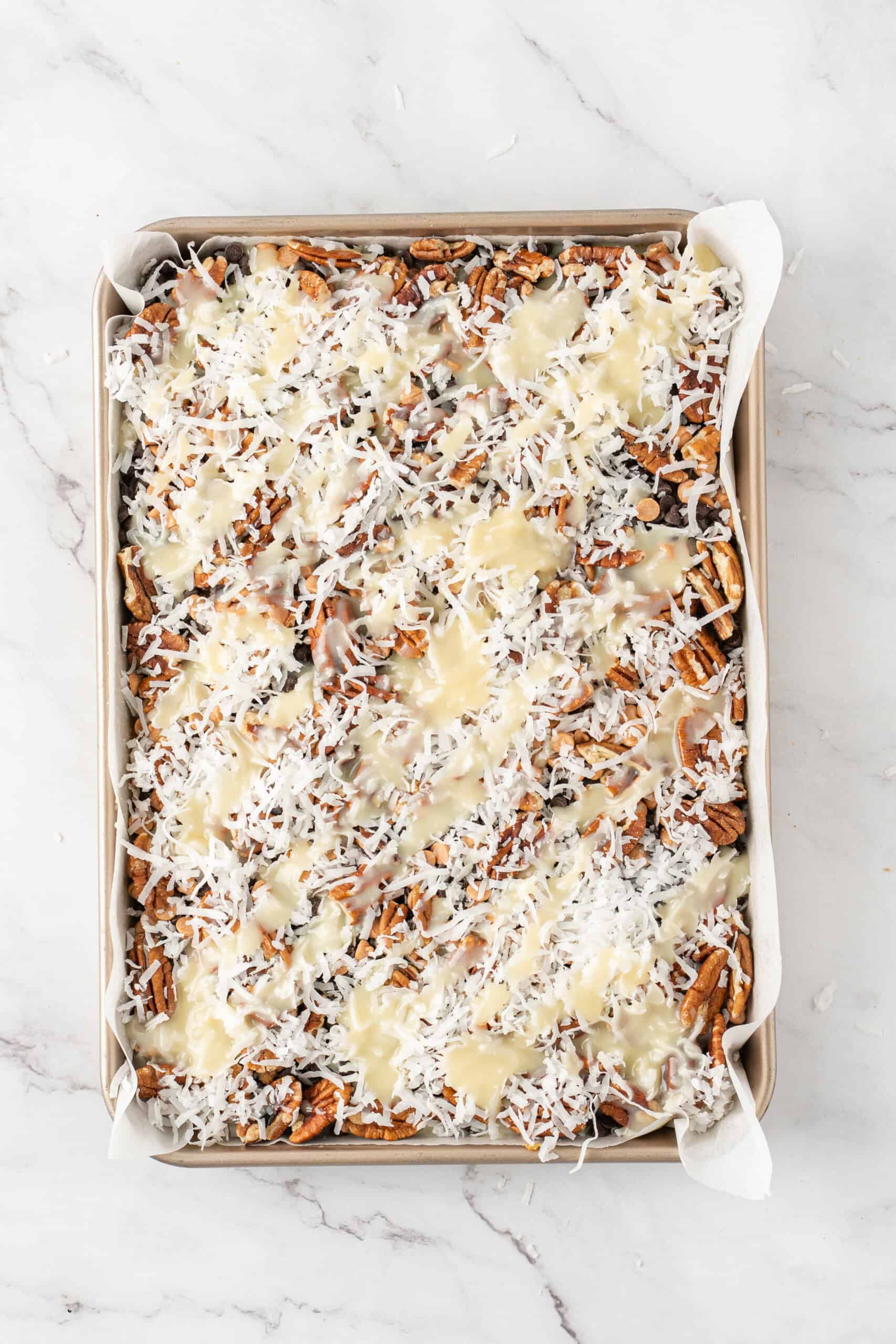 Magic bars topped with sweetened condensed milk before baking.