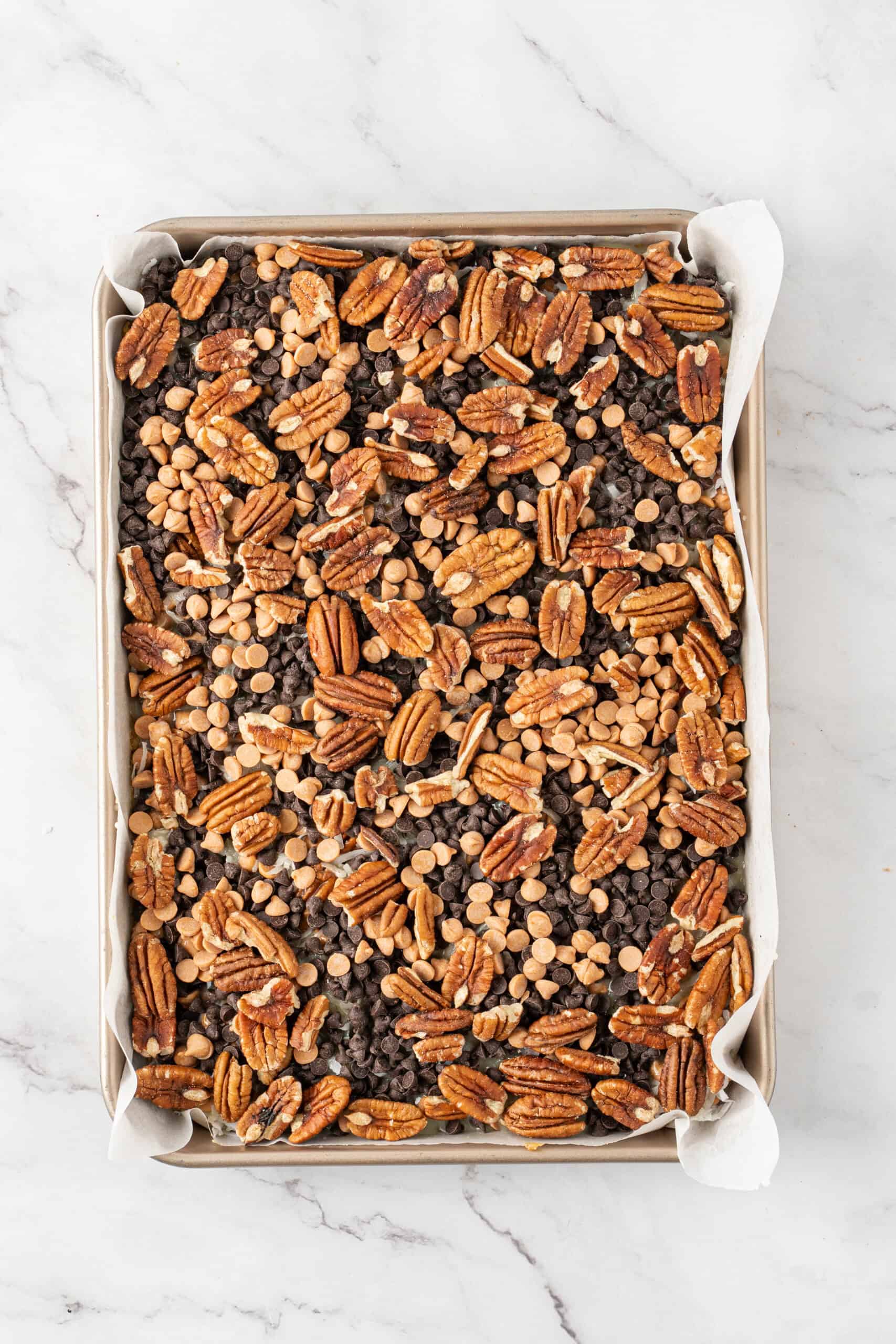 Pecans scattered over chocolate chips and butterscotch chips