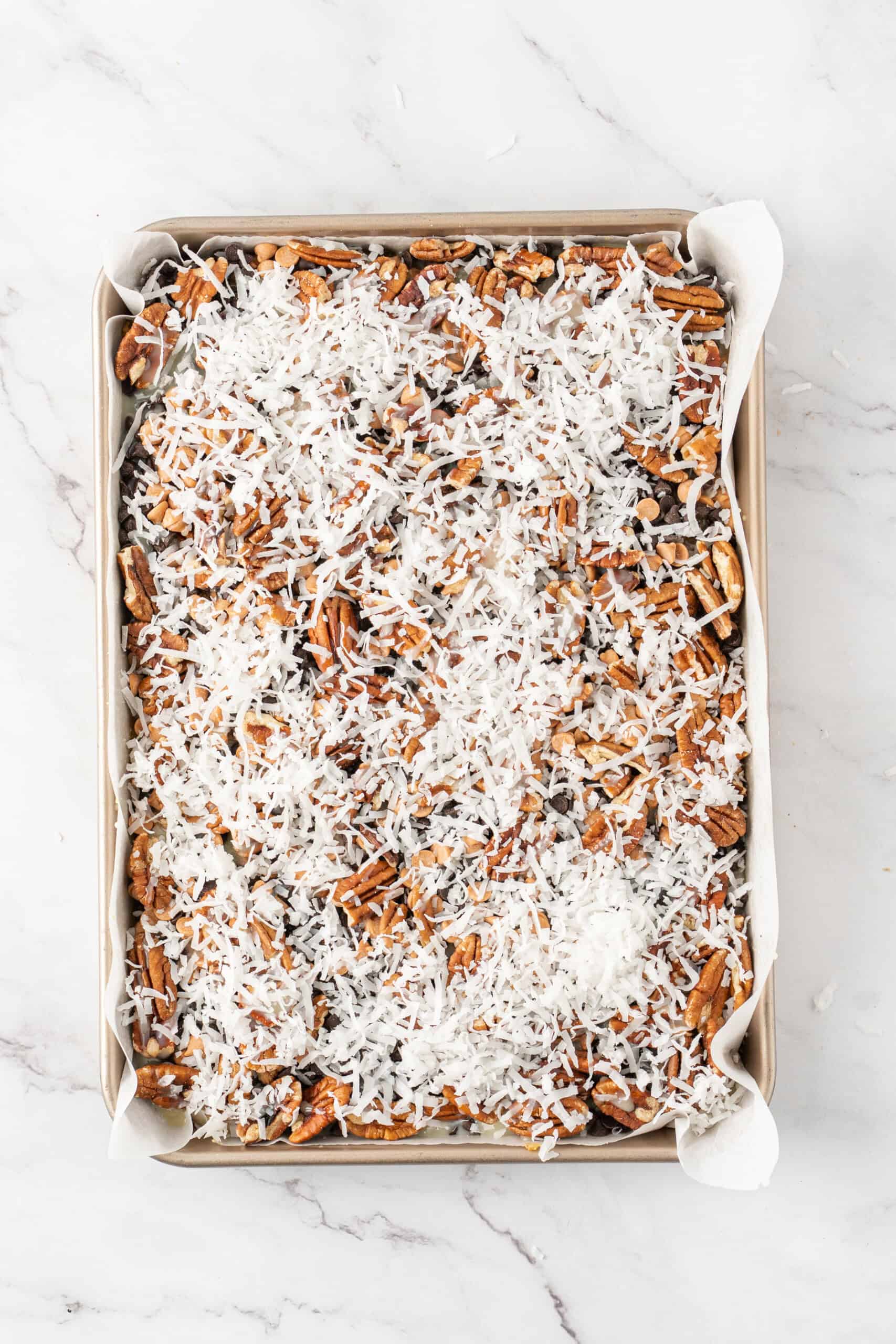 Shredded coconut sprinkled over pecans, chocolate chips, and butterscotch chips