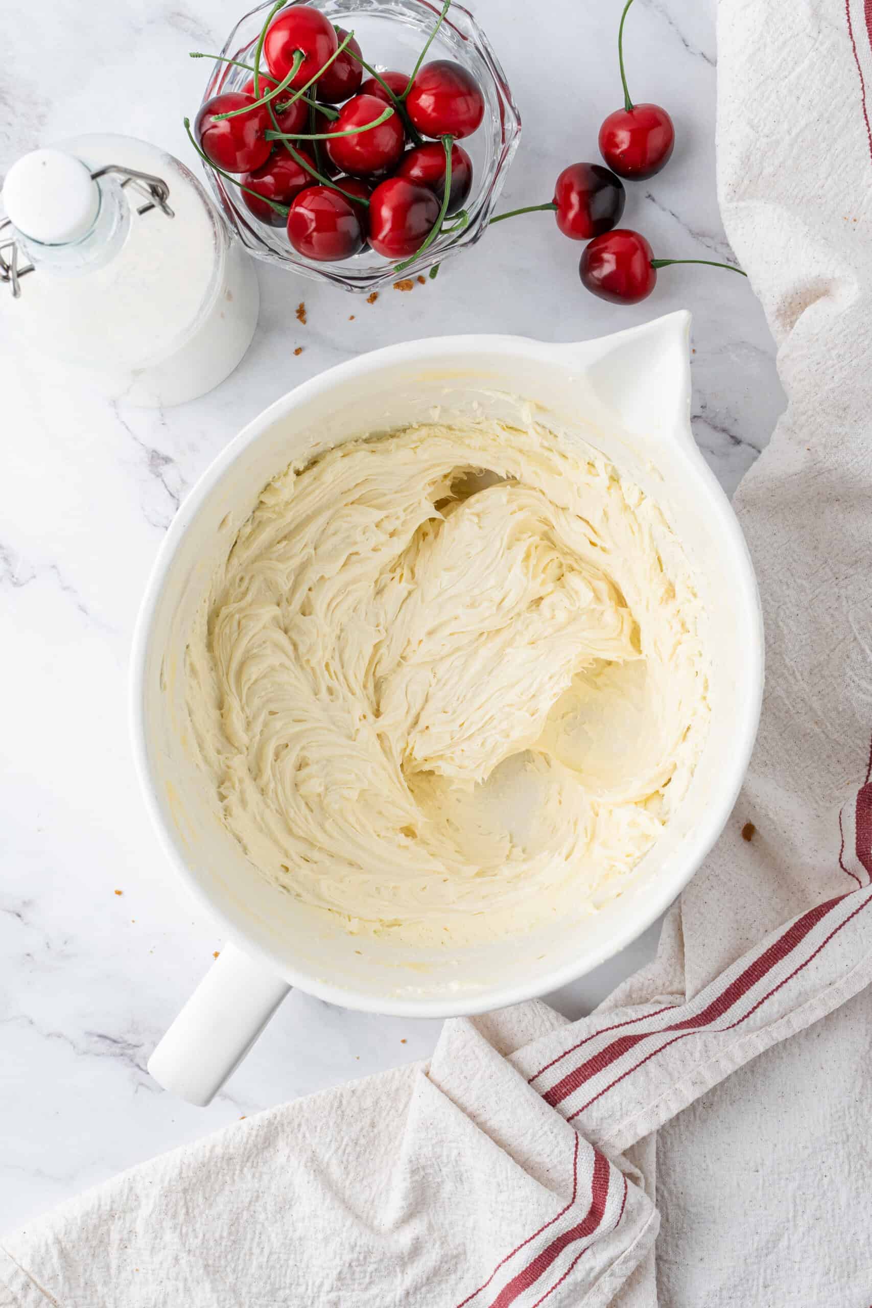 Smooth cheesecake filling mixed with cream cheese, sugar, and vanilla in a white mixing bowl.
