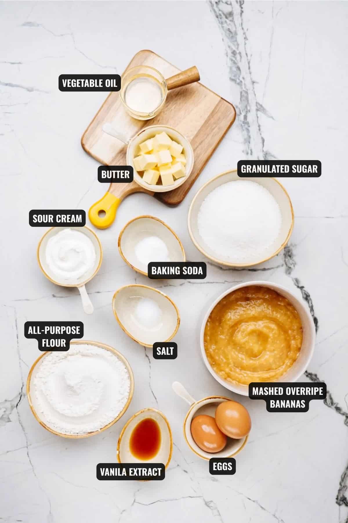 ingredients for banana bread (no nuts) recipe including mashed overripe bananas, eggs, vanilla extract, all-purpose flour, sour cream, butter, vegetable oil, baking soda, and salt