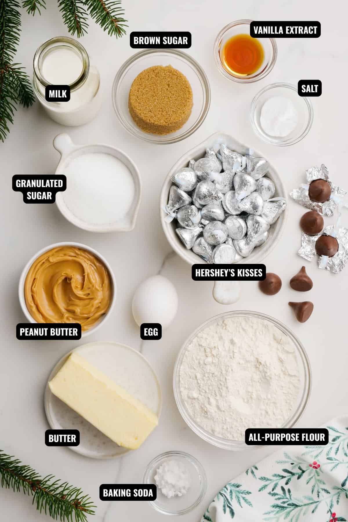 ingredients for peanut butter blossoms including peanut butter, butter, all-purpose flour, hershey's kisses, sugar, baking soda, milk, vanilla extract, and egg