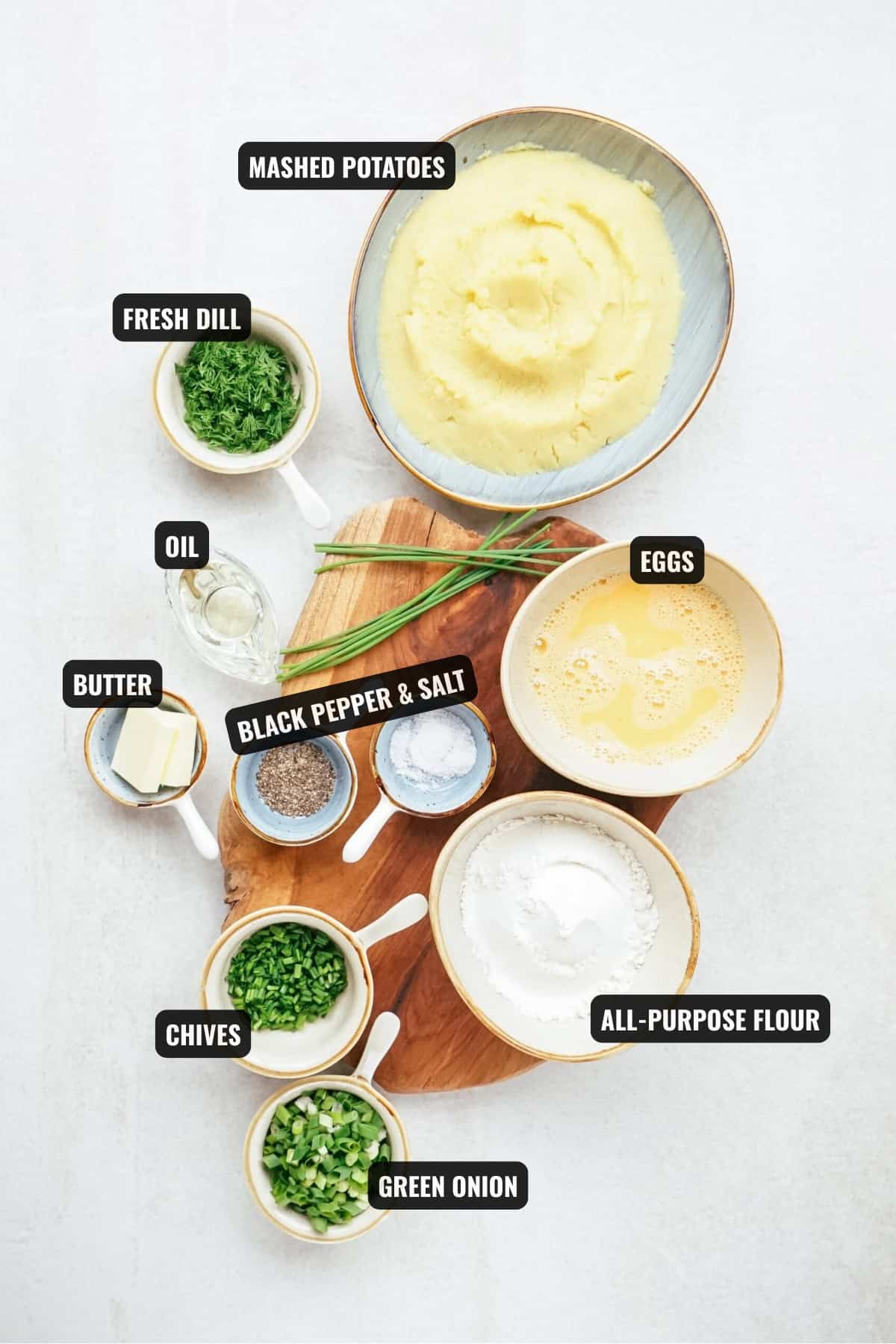 ingredients for potato patties recipe including mashed potatoes, eggs, all-purpose flour, green onion, chives, fresh dill, oil, butter, salt, and black pepper.