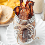 Crispy bacon strips standing upright in a glass jar.