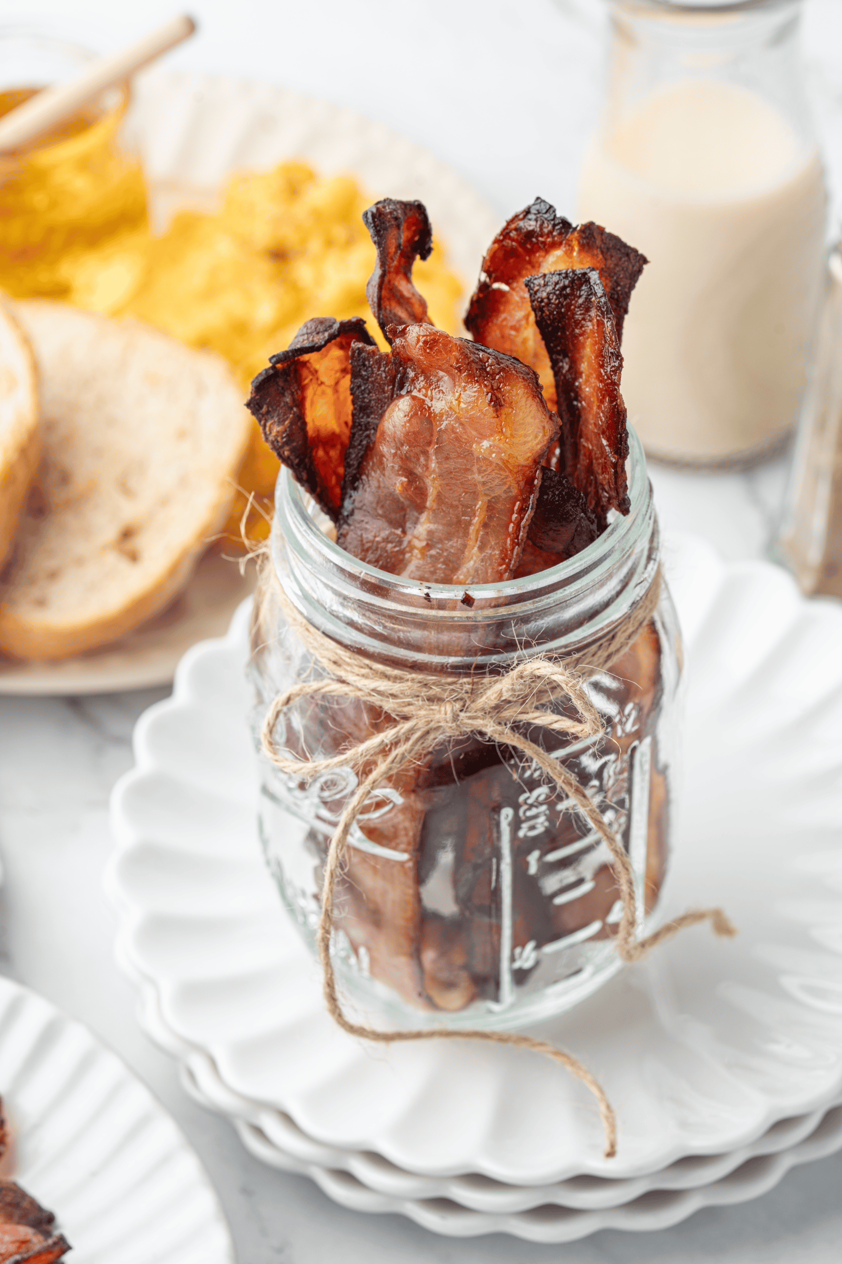 Crispy bacon strips standing upright in a glass jar.