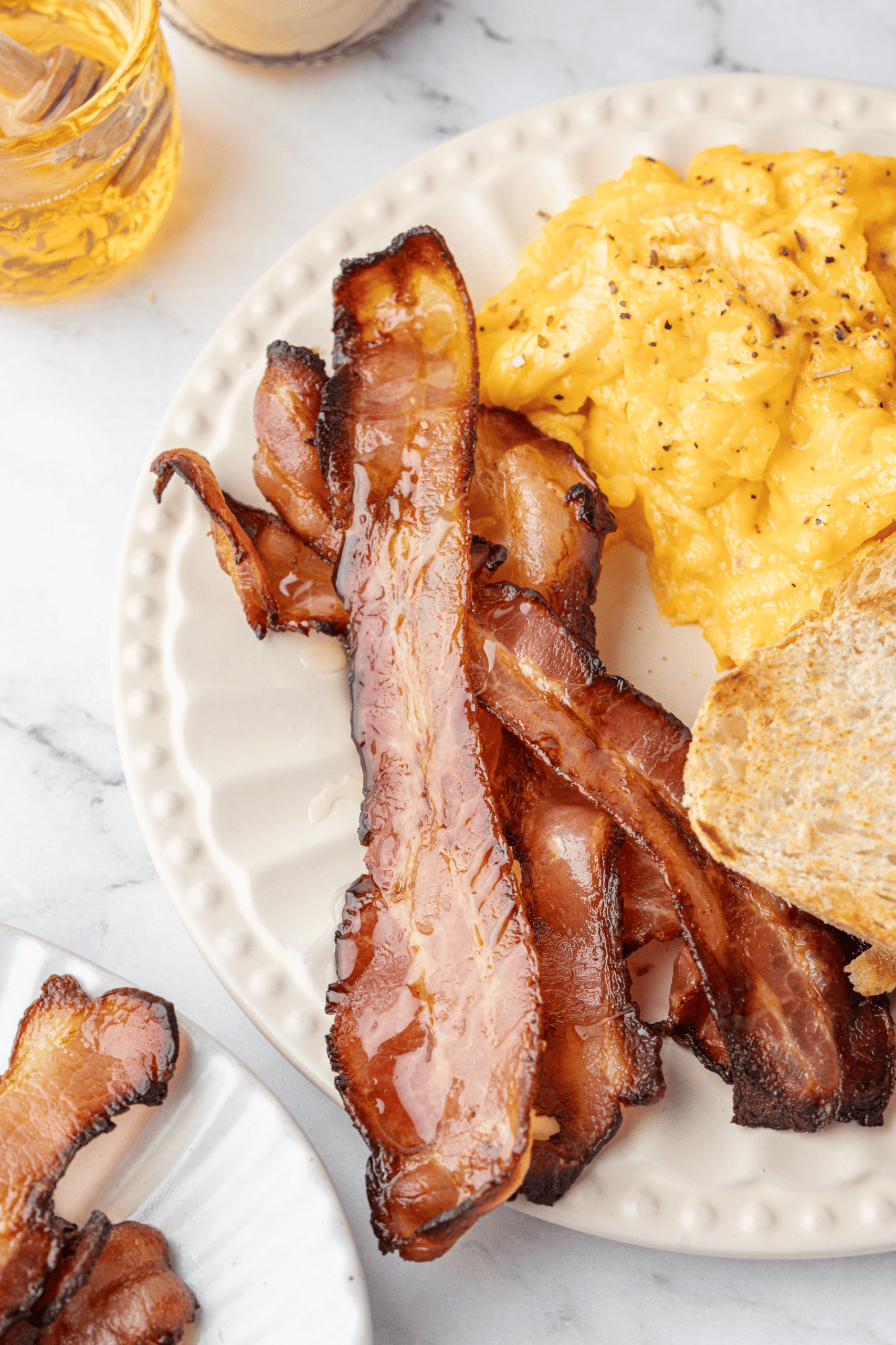 Crispy oven-baked bacon with scrambled eggs and toast.