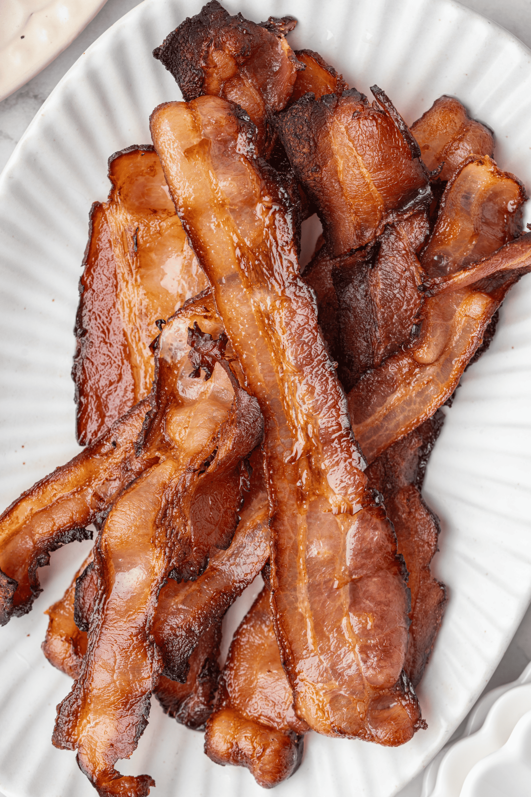 Crispy oven-baked bacon strips on a white plate.