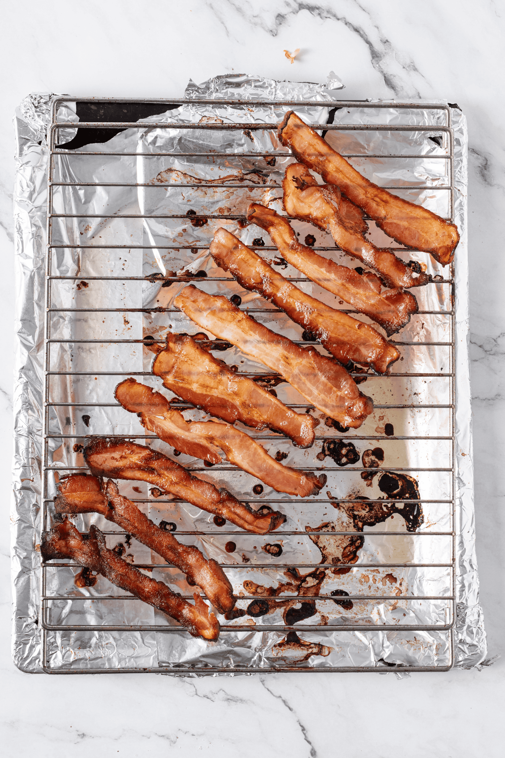 Cooked bacon strips on a wire rack over a foil-lined baking sheet.