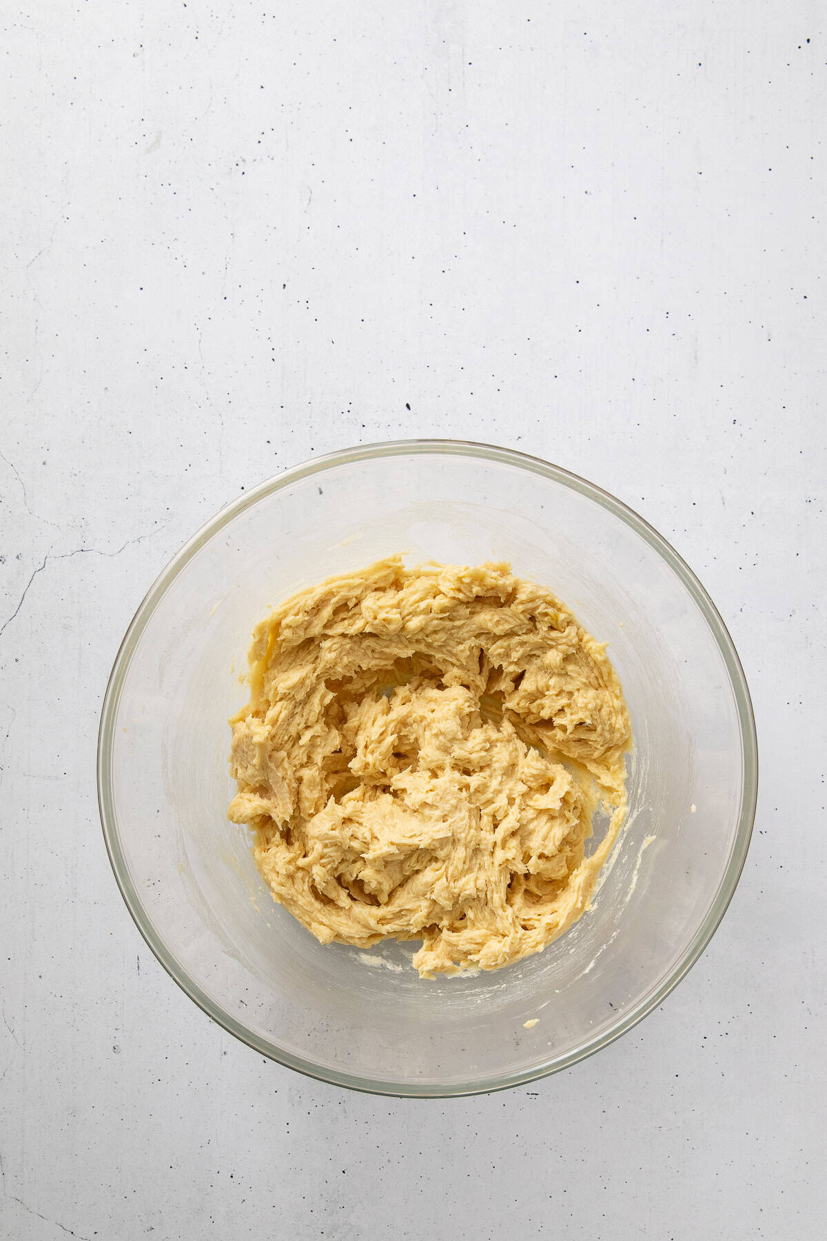 Creamed butter, sugar, eggs, and vanilla mixture in a glass mixing bowl.