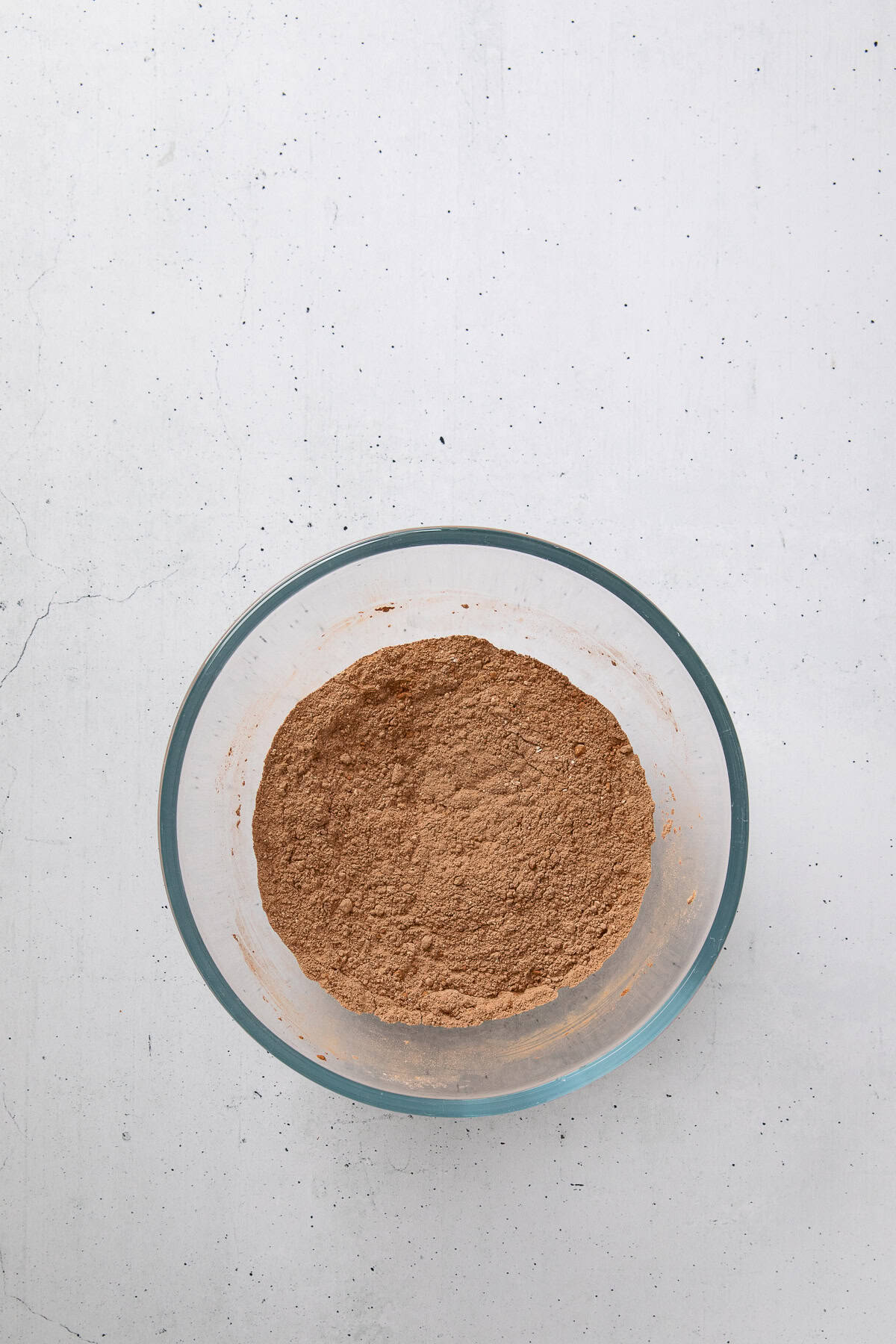 Cocoa powder and dry ingredients mixed in a glass bowl.
