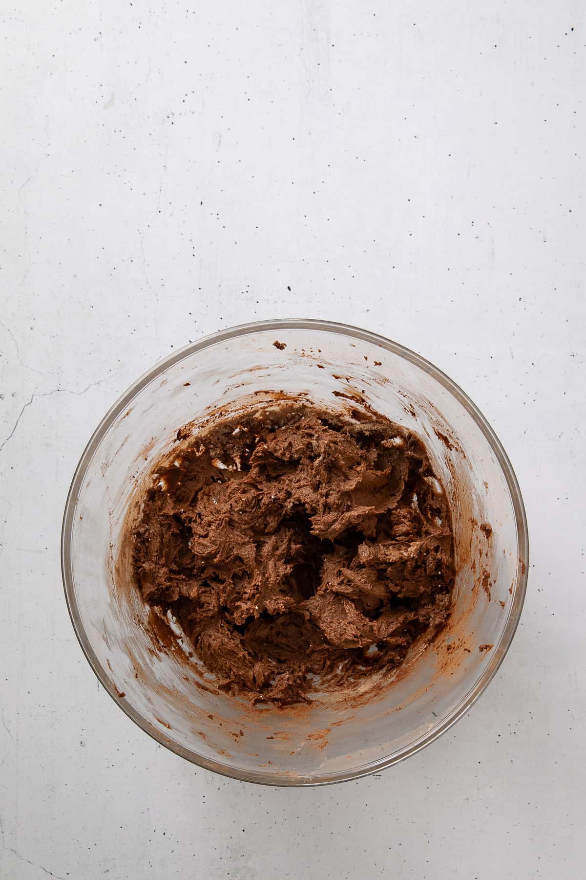 Chocolate cookie dough mixed in a glass bowl.