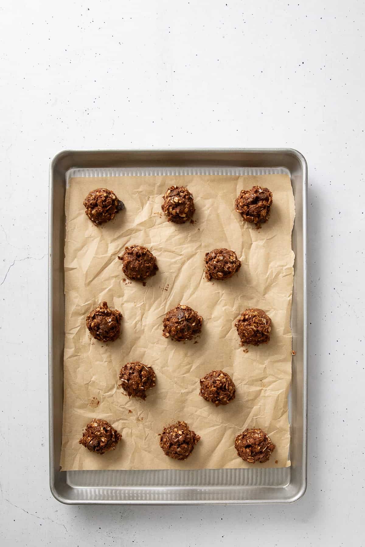 Scoops of cookie dough on a parchment-lined baking sheet.