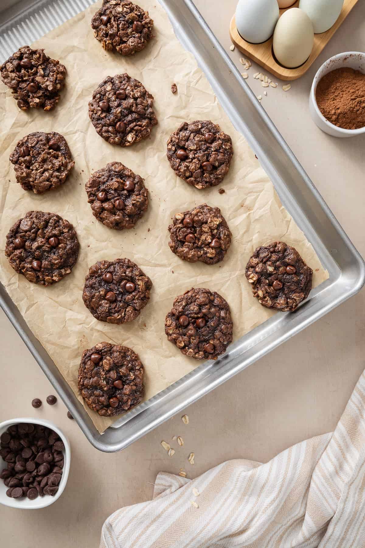 Chocolate oatmeal cookies with chocolate chips on a parchment-lined baking sheet